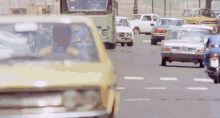 a yellow car with a license plate that says 720 is driving down a busy street