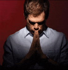 a man with his hands folded in prayer against a red background