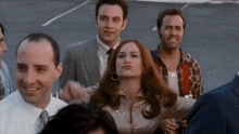 a group of people are standing next to each other in a parking lot and smiling .