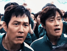 a group of people are playing a game called squid game and one of the players has a surprised look on his face .