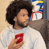 a man wearing a grey nike sweatshirt is holding a red phone