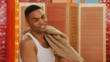 a man in a tank top is holding a sweater over his shoulders