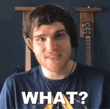 a man wearing headphones and a blue shirt says " what "