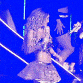 a woman singing into a microphone on a stage with the word rb on the bottom left