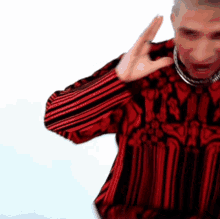 a man wearing a red and black striped shirt is making a funny face .