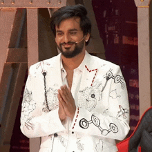 a man wearing a white jacket with drawings on it is smiling