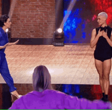 a woman in a purple sweater is watching a man and woman on a stage