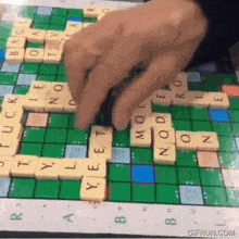 a person playing scrabble on a board that says gifrun.com on it