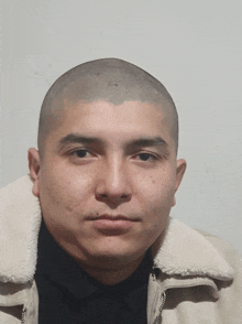 a man with a shaved head wearing a jacket