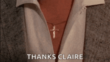 a woman wearing a necklace with a cross pendant and a white shirt .