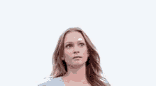 a woman in a blue shirt is standing in front of a white background and looking up .