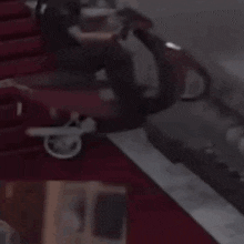 a person is sitting on a red carpet next to a staircase .
