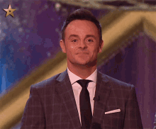 a man in a suit and tie is holding a microphone and smiling