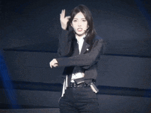 a woman wearing a black jacket and a white shirt is standing on a stage