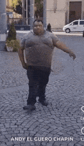 a man is standing on a cobblestone street .