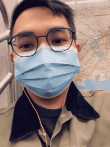 a man wearing glasses and a blue face mask on a subway