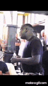 a man in a black shirt is holding a bottle of water while standing in a crowd .