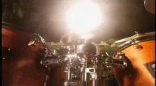 a man is playing drums in a dark room with a light shining through the drums .