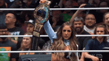 a woman in a wrestling ring holds up a world heavyweight title