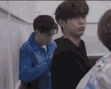 a man in a blue jacket stands next to another man in a black shirt