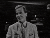 a man in a suit is holding a microphone and smiling