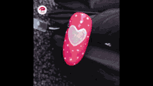 a red nail with polka dots and a heart on it .