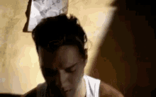 a man is sitting in front of a wall with a piece of paper stuck to his head .