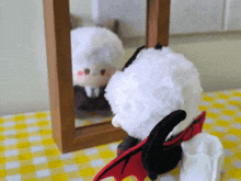 a stuffed animal with horns and wings looks at its reflection in a mirror