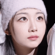 a close up of a woman 's face wearing a white beanie