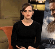 a woman in a black shirt is sitting in front of a poster for the movie no time to die