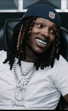 a man with dreadlocks is wearing a hat and a necklace .