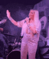 a woman is standing on a stage holding a microphone and singing into it .