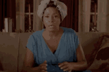 a woman sitting on a couch with curlers on her hair
