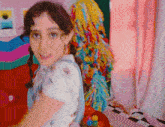 a girl with pigtails is standing in a room with a colorful christmas tree in the background
