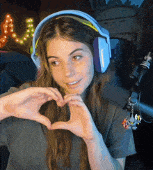 a girl wearing headphones making a heart shape with her hands