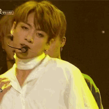 a man in a white shirt with a microphone in his mouth is on a stage .