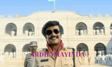 a man in a police uniform stands in front of a building with the words ardhana mayinda written on the bottom