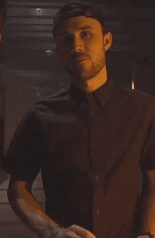 a man wearing a black shirt and a baseball cap is holding a clapper board