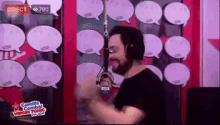 a man wearing headphones is dancing in front of a microphone in front of a wall of speech bubbles .