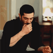 a man in a black shirt is eating something from his hand