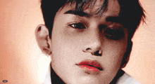 a close up of a young man 's face with red lips and black eyes .