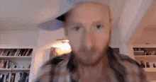 a man with a beard wearing a plaid shirt looks at the camera