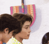 a close up of a man 's face with a colorful bag hanging on the wall behind him
