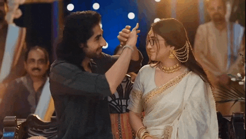 a man and a woman are dancing together in a room . the woman is wearing glasses .
