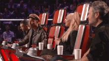 a group of people sitting in red chairs with cups