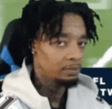 a man with dreadlocks is sitting in a chair looking at the camera .