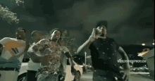 a group of people are dancing in a parking lot at night with a worldstarhiphop.com logo in the corner .