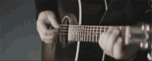a man is playing an acoustic guitar in a black suit .