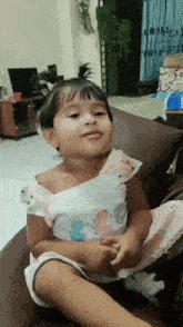 a little girl is sitting on a couch and making a face