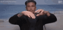 a man is making a heart with his hands on the beach .